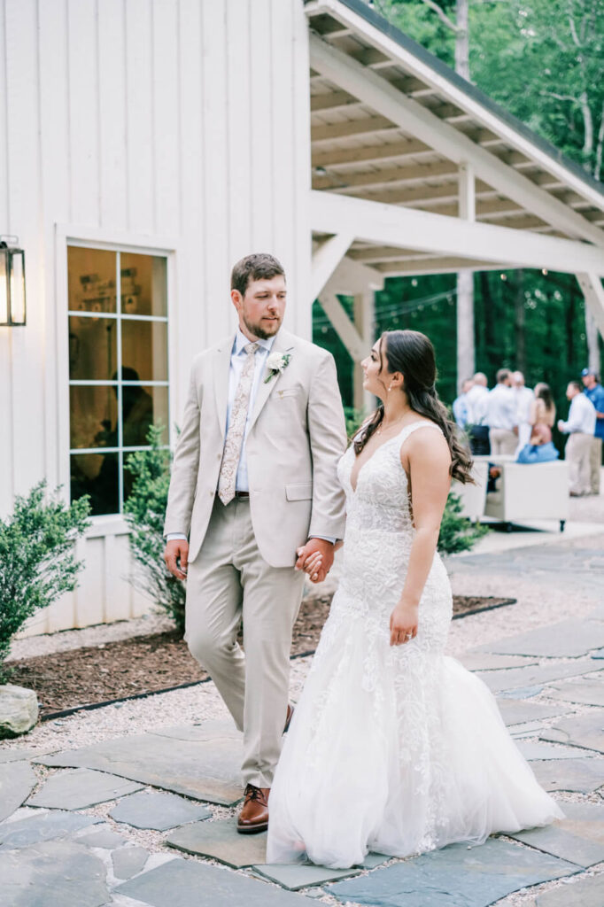 A tender moment as the newlyweds walk together, gazing at each other outside the reception venue.