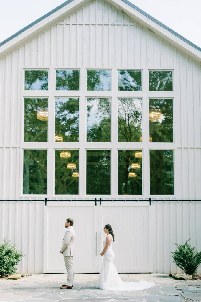 First look moment outside Carolina Grove’s grand barn, as Bonnie approaches Aiden before the ceremony.