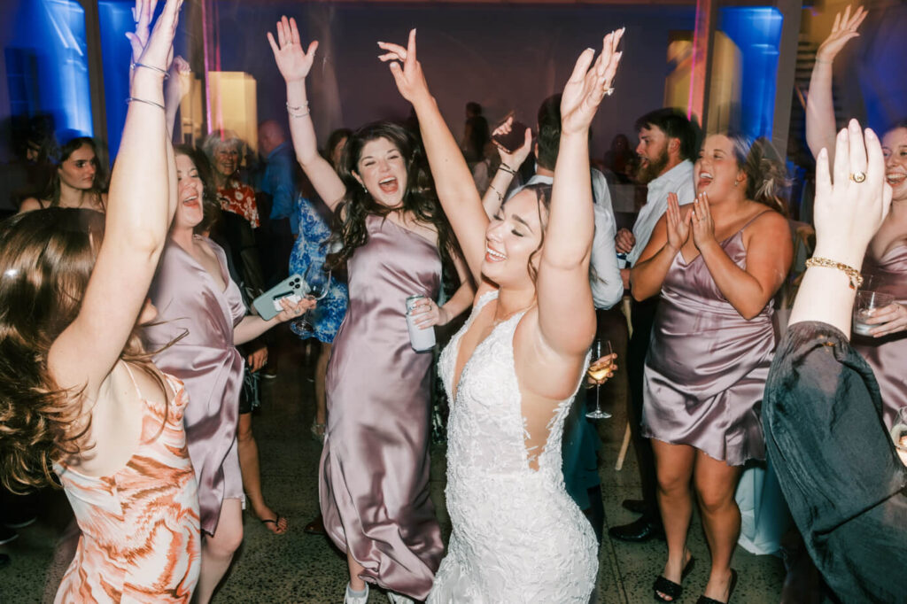 Bride and bridesmaids dancing in celebration – The bride and her closest friends joyfully dancing, arms raised in celebration during the reception.