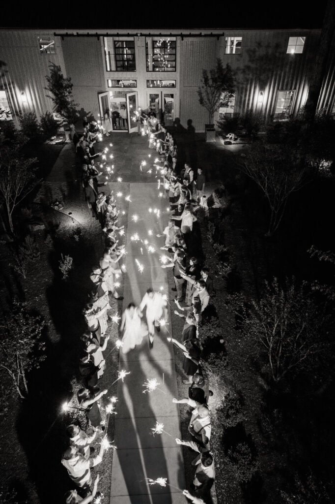 Aerial view of the sparkler exit send-off – A magical nighttime view of the couple running through a tunnel of sparklers, surrounded by loved ones.