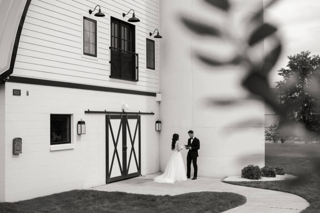 Bride and Groom Sharing Private Vow Exchange – An intimate moment of the couple reading personal vows outside Sweeney Barn, framed by architectural and natural elements.