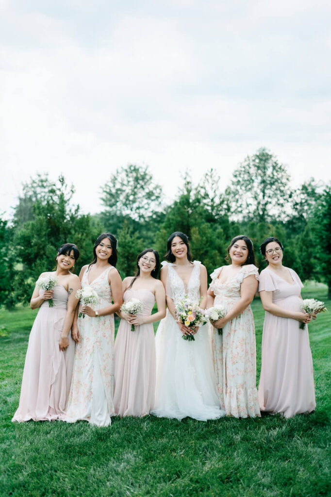 Bridal Party in Soft Pastel Dresses at Sweeney Barn – The bride stands with her bridesmaids in a dreamy lineup, their pastel dresses perfectly complementing the lush outdoor setting of Sweeney Barn.