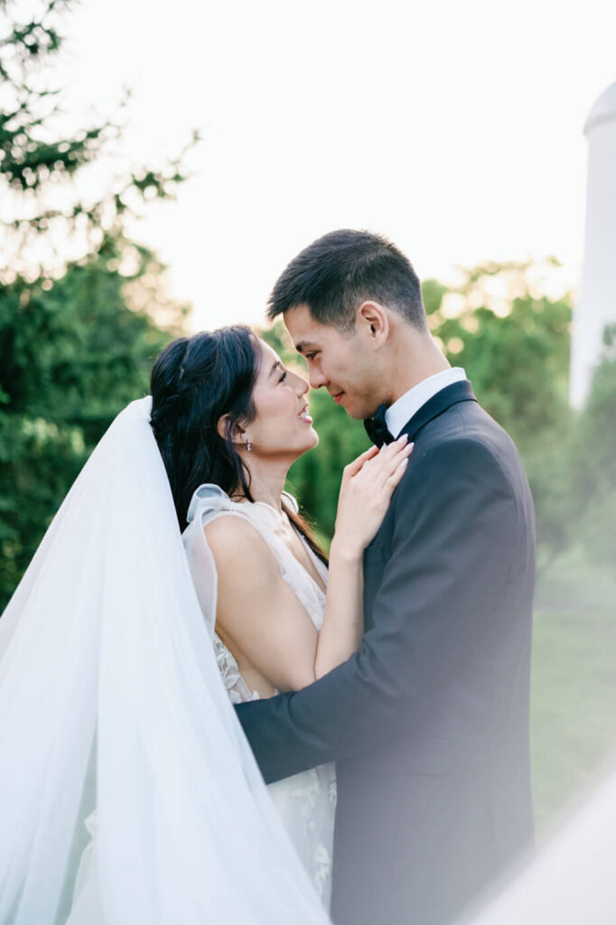 Close-up of bride and groom forehead to forehead – The bride and groom share a tender moment, foreheads touching with radiant smiles as the golden sunset glows around them.