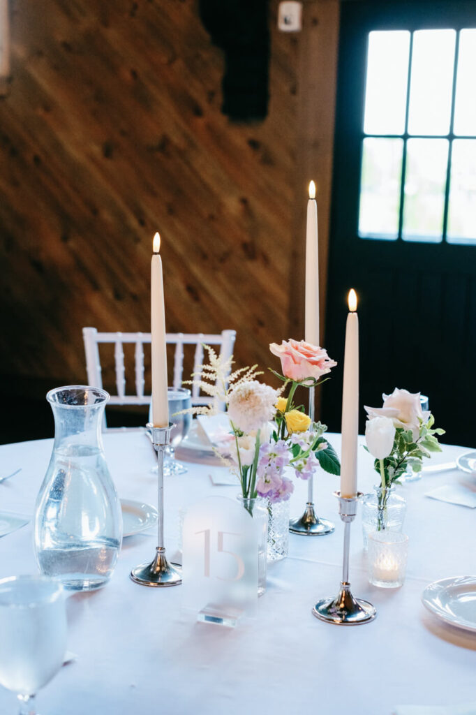 Candlelit wedding reception table decor – A beautifully set reception table with soft candlelight, pastel florals, and crystal glassware creates an intimate and romantic atmosphere.