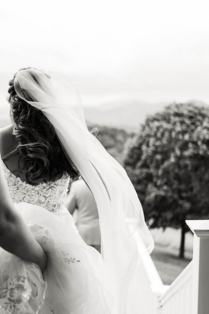 Bride with flowing veil descending stairs to father daughter first look, featured in an Asheville mountain wedding photographed by The Reeses.