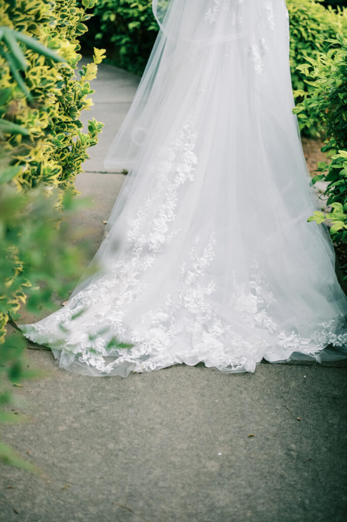 Bride’s lace gown train trailing on a path, part of an Asheville mountain wedding by The Reeses.