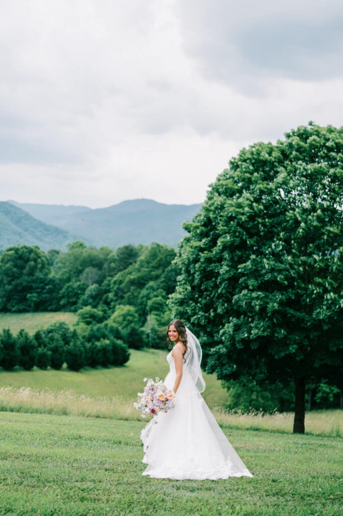 Bride with flowing veil walking outdoors, part of an Asheville mountain wedding photographed by The Reeses.