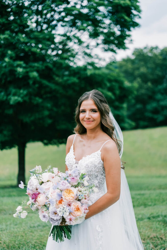 Bride smiling with a pastel floral bouquet, part of an Asheville mountain wedding captured by The Reeses.