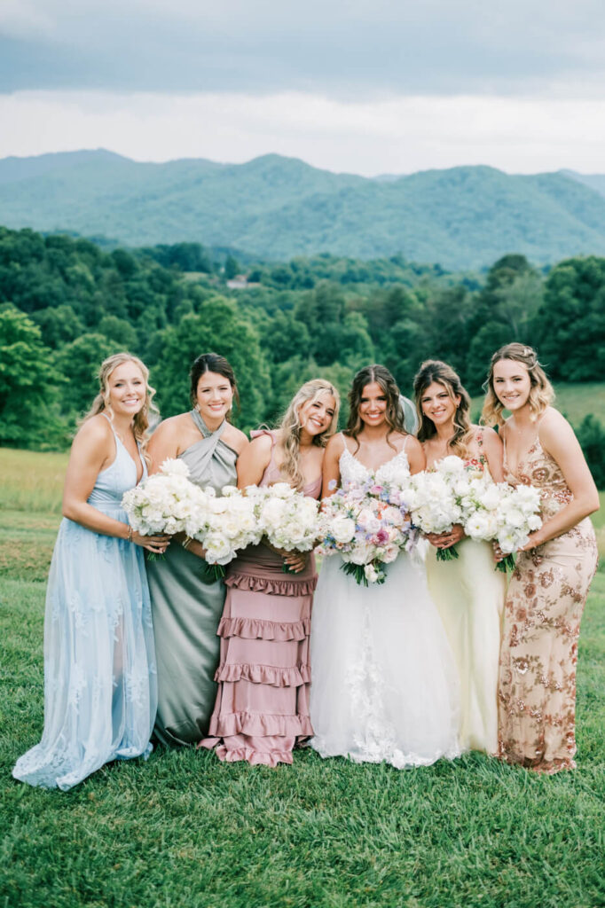 Bride and bridesmaids holding bouquets with mountain views, part of an Asheville mountain wedding by The Reeses.