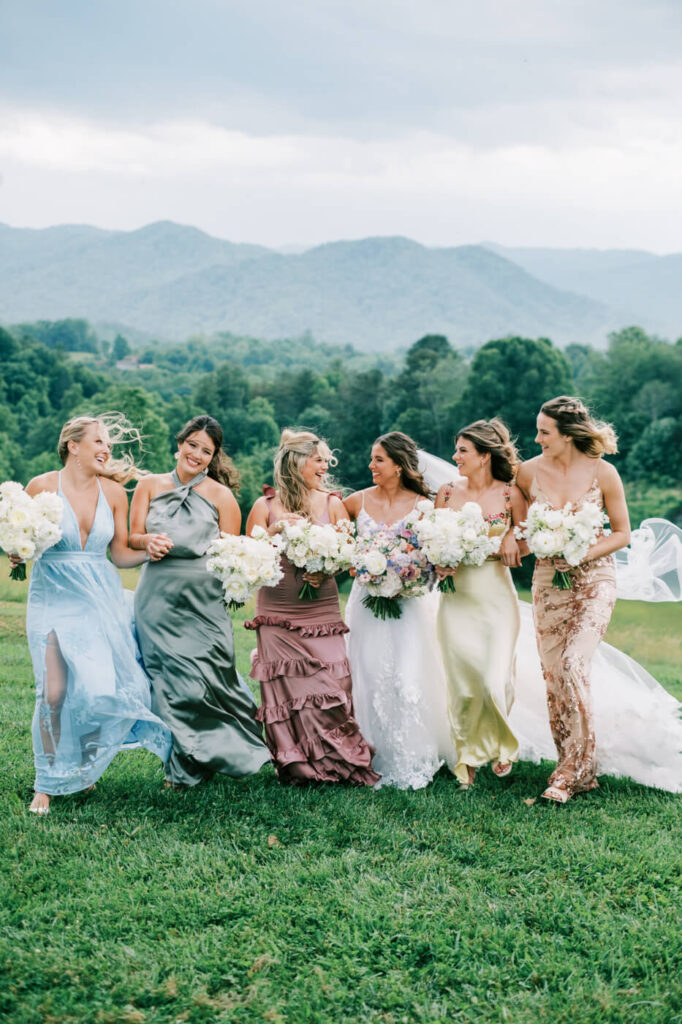 Bride & Bridesmaids in pastel dresses walking with bouquets, part of an Asheville mountain wedding captured by The Reeses.