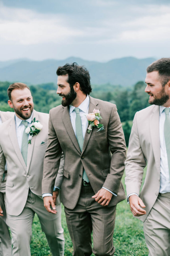 Groom & groomsmen walking with blue ridge mountains behind, part of an Asheville mountain wedding captured by The Reeses.