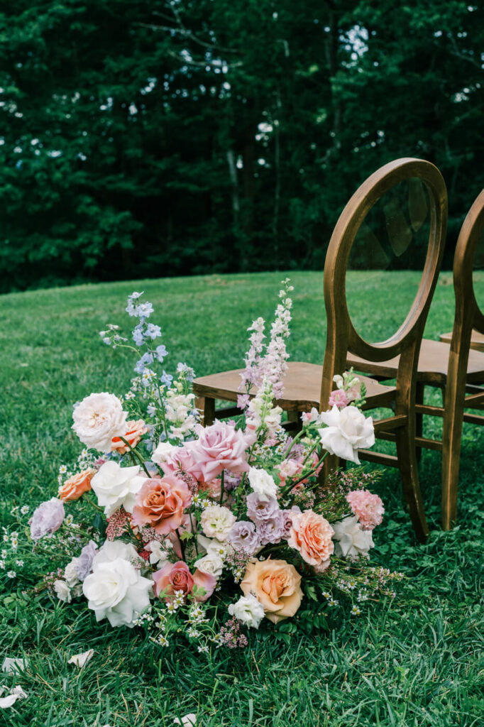 Close-up of colorful ceremony floral arrangement on the ground, featured in an Asheville mountain wedding by The Reeses.