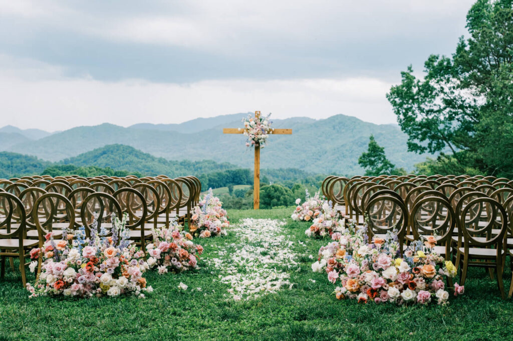 Ceremony setup with wooden cross and floral decorations, part of an Asheville mountain wedding by The Reeses.