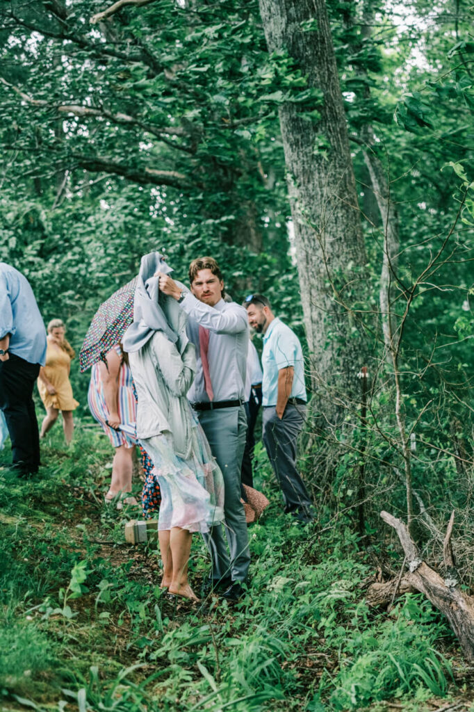 Guests taking cover from the rain, part of an Asheville mountain wedding captured by The Reeses.