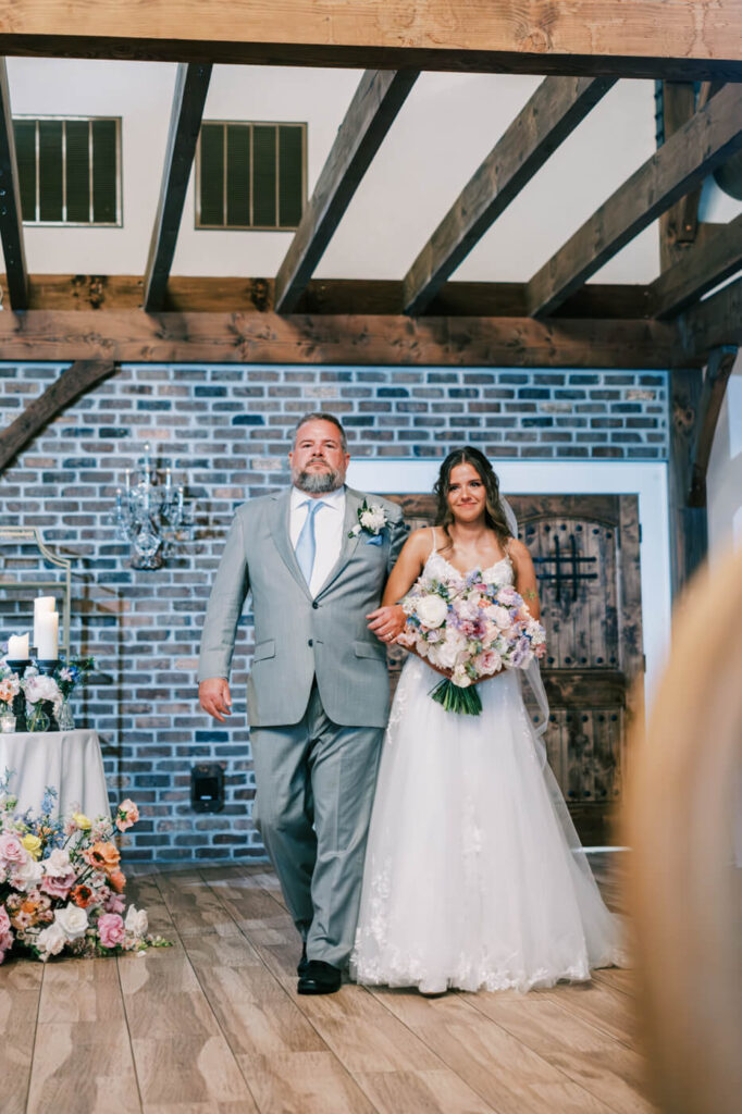 Father walking bride down the aisle with bouquet, part of an Asheville mountain wedding photographed by The Reeses.