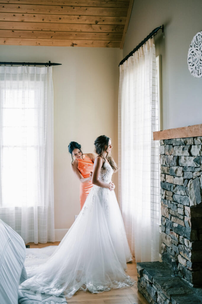 Bride in a white gown with a her mother adjusting her dress for an Asheville mountain wedding by The Reeses.