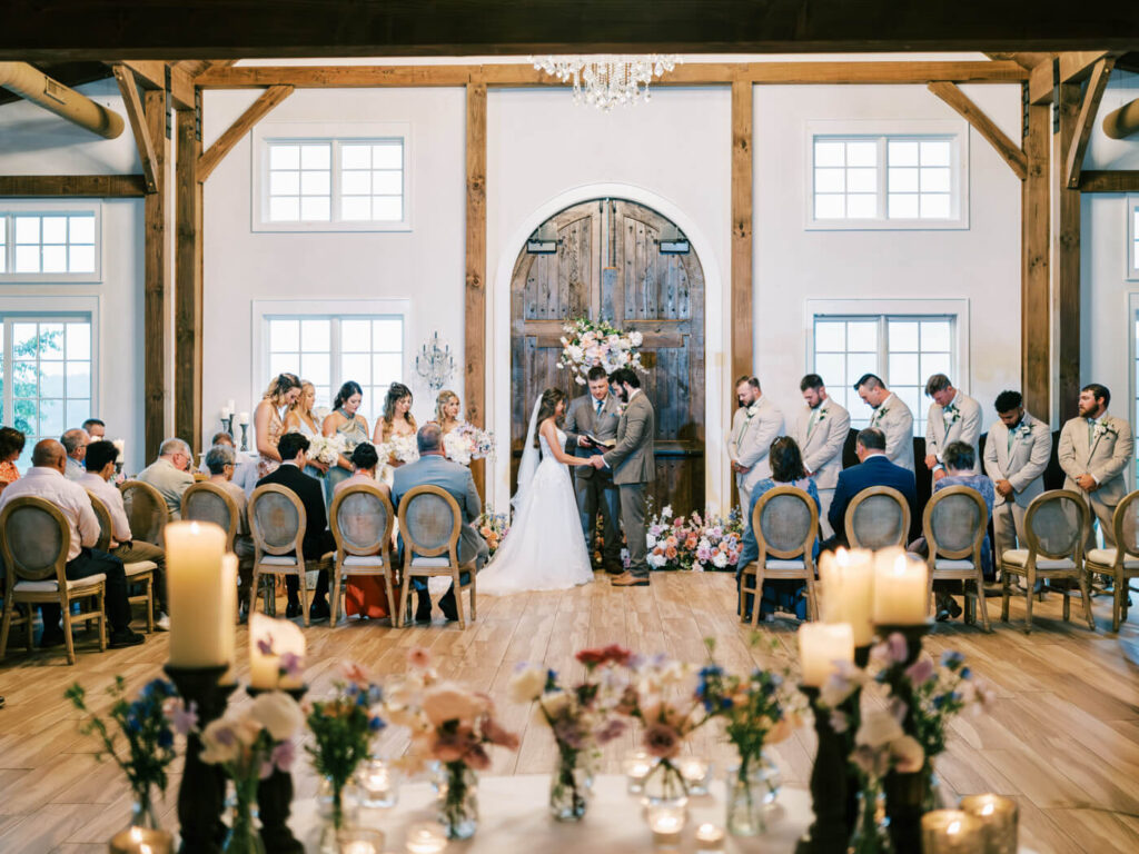 Bride and groom exchanging vows indoors with floral decor, part of an Asheville mountain wedding captured by The Reeses.