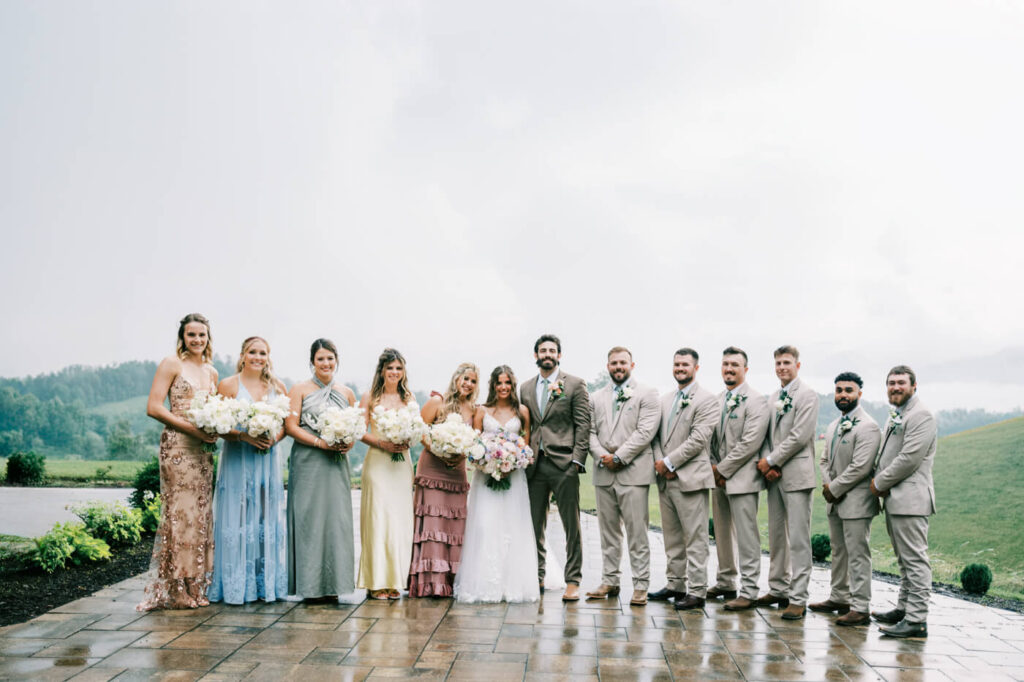 Wedding party posing on a wet patio with mountains, part of an Asheville mountain wedding by The Reeses.