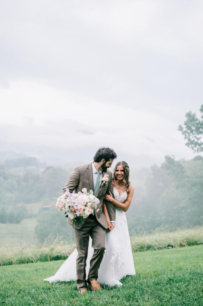 Bride and groom playfully walking hand in hand in the blue ridge mountains, part of an Asheville mountain wedding by The Reeses.