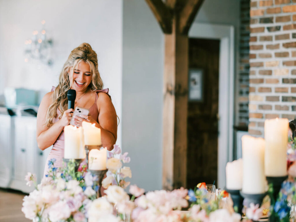 Emotional Maid of Honor Speech at Asheville Wedding – A joyful maid of honor gives a heartfelt speech, surrounded by glowing candlelight and soft pastel florals at a mountain wedding reception.