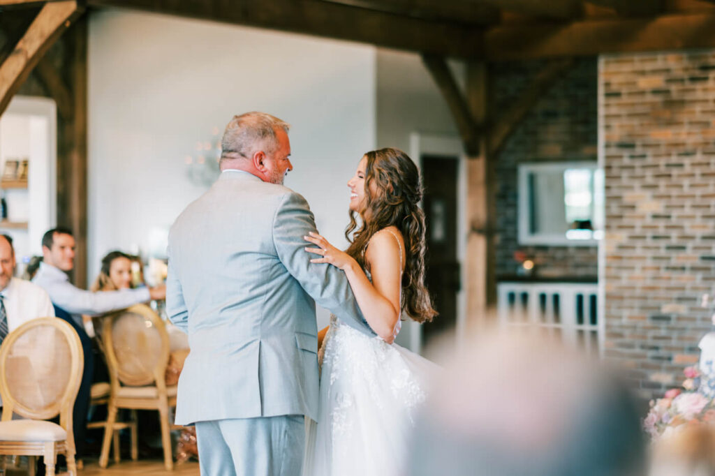 Father-Daughter Dance at Asheville Mountain Wedding – A touching father-daughter dance as the bride smiles warmly at her father in a beautifully decorated rustic wedding venue.