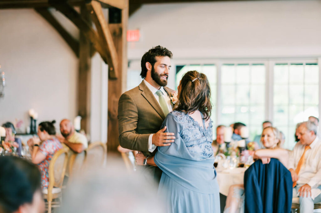 Groom dancing with mother during Asheville mountain wedding reception – The groom shares a heartfelt dance with his mother, surrounded by warm candlelight and rustic elegance in an Asheville wedding venue.