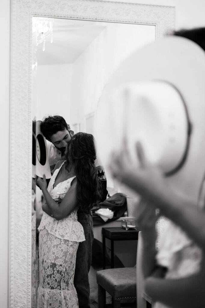 Romantic black and white mirror reflection of bride and groom – The bride and groom share a private kiss, reflected in an ornate mirror, adding a timeless and intimate touch to their Asheville wedding photography.