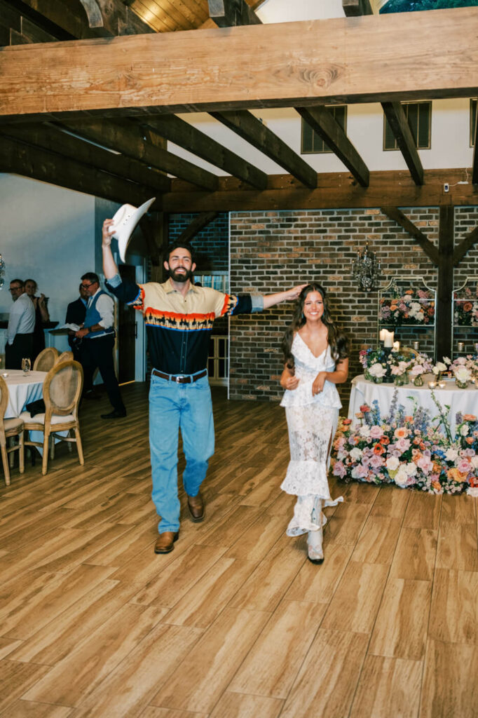 Bride and groom enter reception in Western-inspired outfits – The couple makes a fun, stylish entrance at their reception, with the groom in a cowboy hat and boots, adding a unique twist to their Asheville mountain wedding.