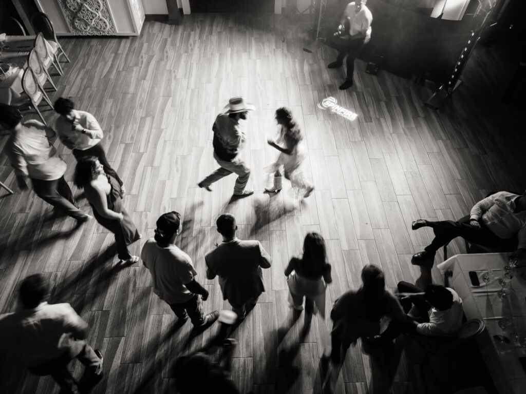 Overhead view of wedding guests dancing during Asheville reception – Guests celebrate on the dance floor, with soft lighting and shadows capturing the lively energy of this rustic mountain wedding reception.