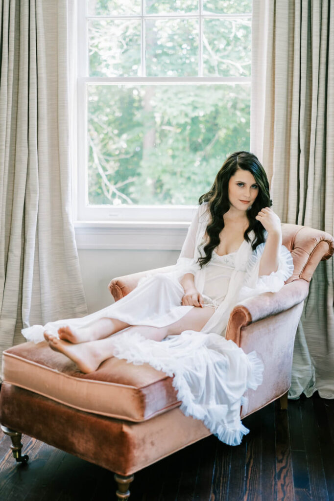 Bride’s Morning Portrait at McAlister-Leftwich House – The bride lounges gracefully on a vintage chaise in a sunlit room, draped in a delicate white robe, exuding timeless elegance before getting ready for her wedding day.