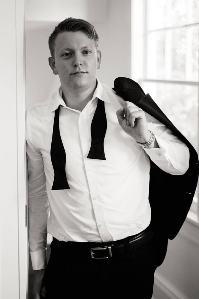 Black-and-White Groom Portrait Before the Ceremony – A timeless black-and-white portrait of the groom, showcasing a confident expression as he adjusts his suit and prepares to meet his bride.