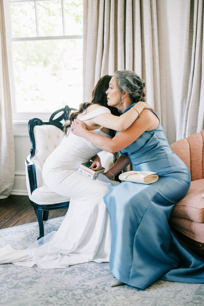 Bride and Mother Embracing Before the Ceremony – A touching moment as the bride and her mother share a warm embrace, highlighting the deep emotions of the day in a luxurious, light-filled setting.