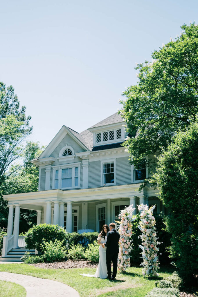 Outdoor wedding ceremony at McAlister-Leftwich House – A picturesque view of the couple exchanging vows in front of the historic McAlister-Leftwich House, framed by vibrant floral arrangements and lush greenery.