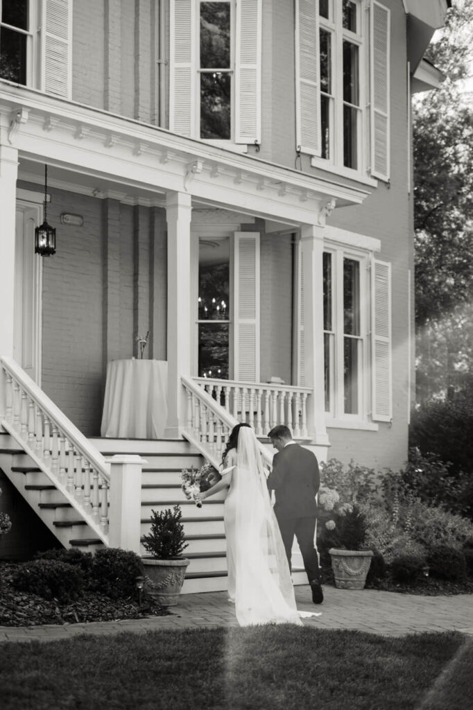 Bride and Groom’s Grand Exit from Historic Venue – The newlyweds walk hand-in-hand up the steps of the McAlister-Leftwich House, a charming Southern mansion with elegant white columns.