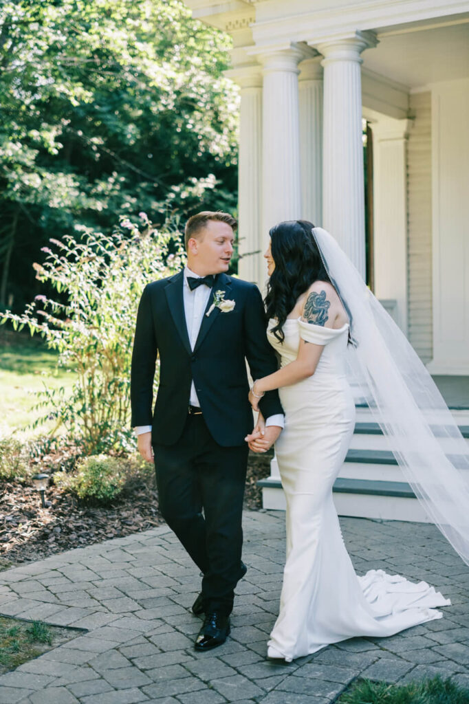 Bride and Groom Holding Hands After Saying 'I Do' – A joyful moment as the newlyweds walk together, looking at each other lovingly, in the garden setting of their wedding venue.