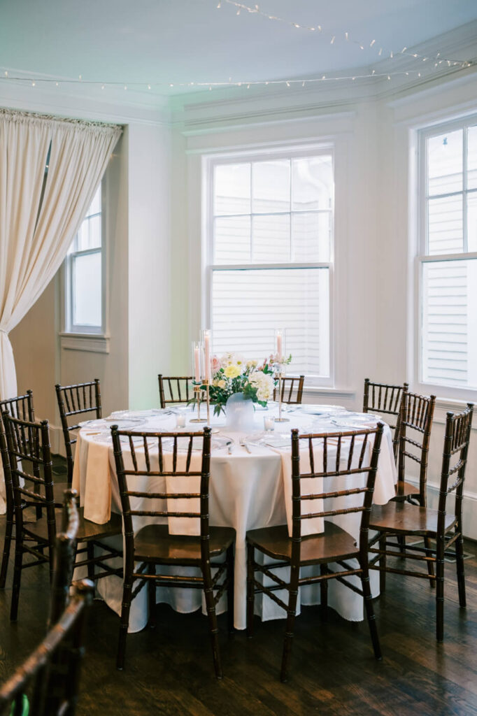 Elegant Reception Table Setup at McAlister-Leftwich House – A round wedding reception table with classic wooden chairs, candlelight, and floral centerpieces creates a timeless and inviting ambiance.