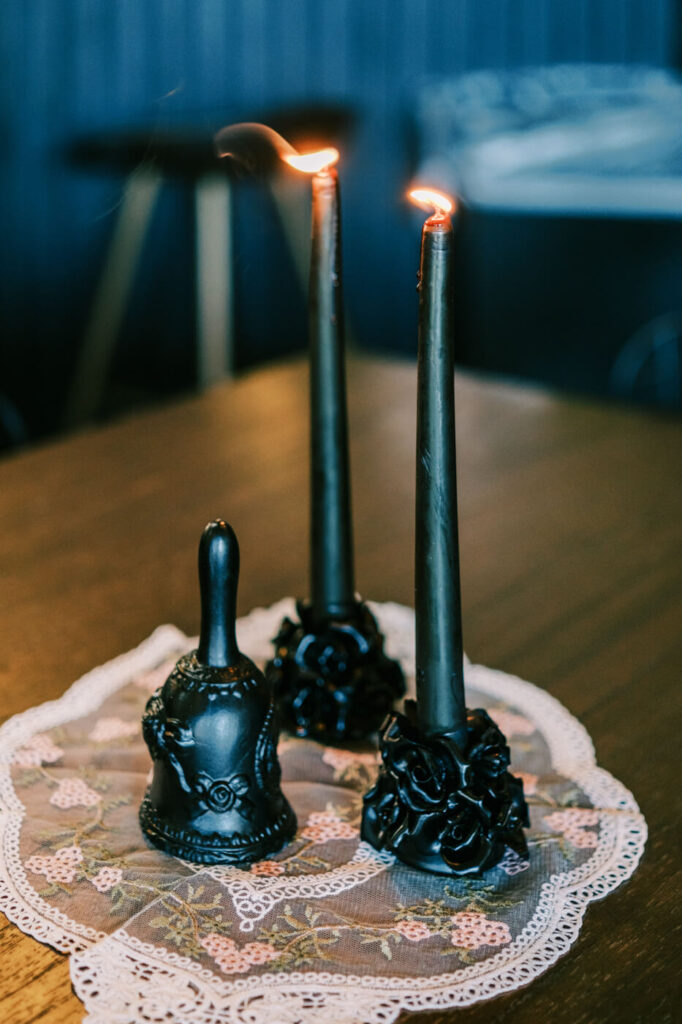 Elegant black candlesticks with intricate floral bases and a bell centerpiece on a lace runner at a Greensboro, NC wedding rehearsal dinner.