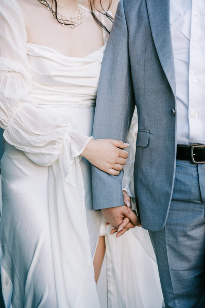 A close-up of the bride holding the groom’s arm, showcasing her soft ivory gown and elegant pearl necklace at McAlister-Leftwich House.