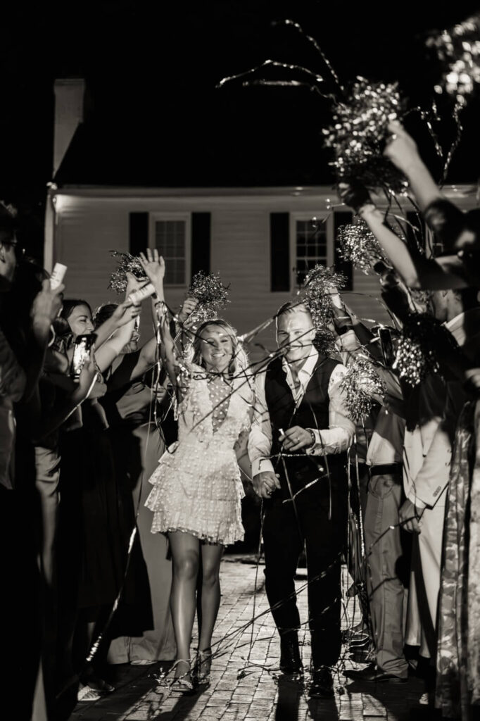 Grand wedding exit with streamers at The Historic Robertson House – The newlyweds walk hand in hand through a tunnel of friends and family waving shimmering streamers in a joyful send-off.