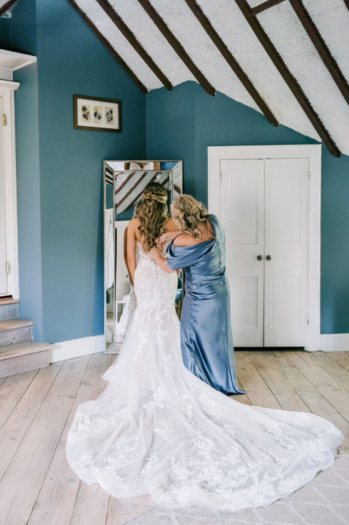 Bride's mother fastening the wedding gown in the bridal suite at Historic Robertson House, capturing a heartfelt moment before the ceremony.