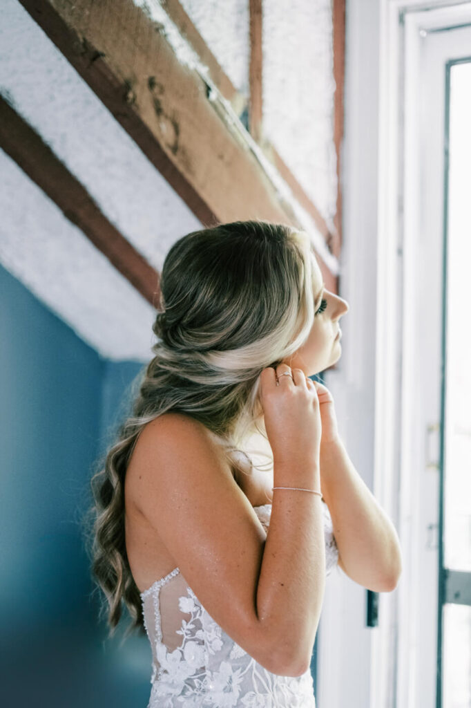 Bride putting on earrings in the sunlit bridal suite at Historic Robertson House, preparing for her wedding day.