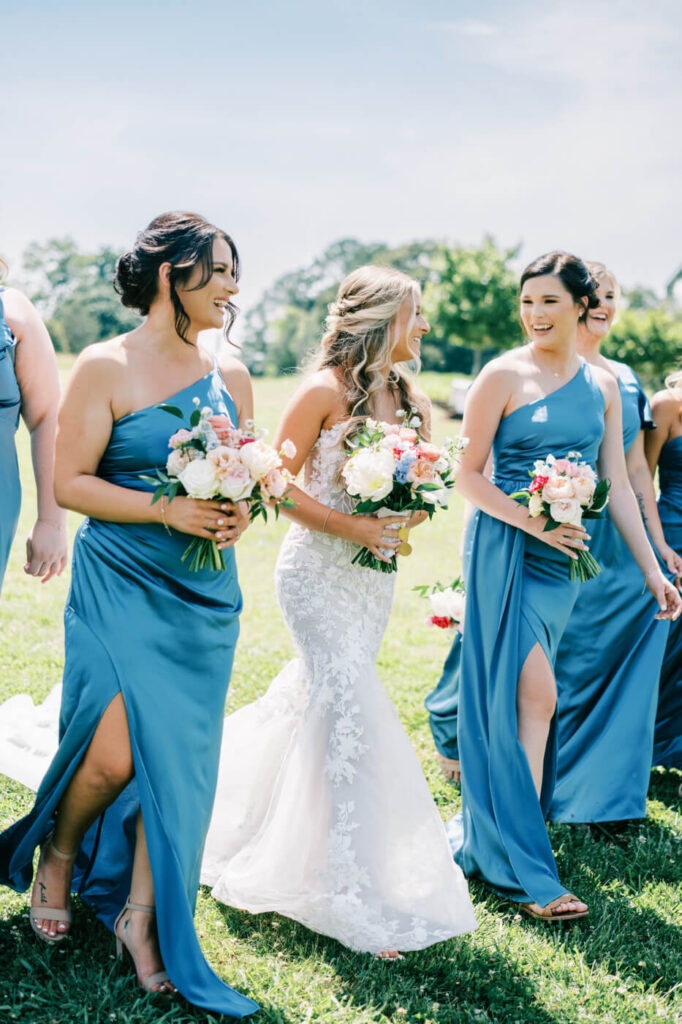 Bride laughing with her bridesmaids as they walk across the lawn of Historic Robertson House, showcasing a timeless Southern wedding style.