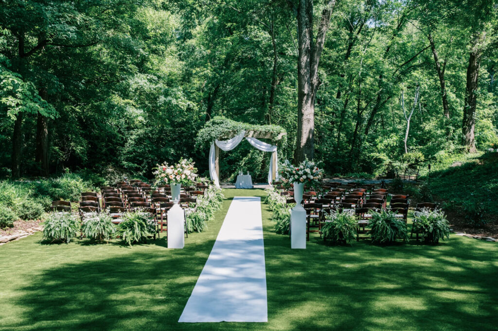 Romantic outdoor wedding ceremony setup at The Historic Robertson House – A breathtaking ceremony site with white drapery, lush greenery, and floral arrangements, creating an enchanting wedding atmosphere.