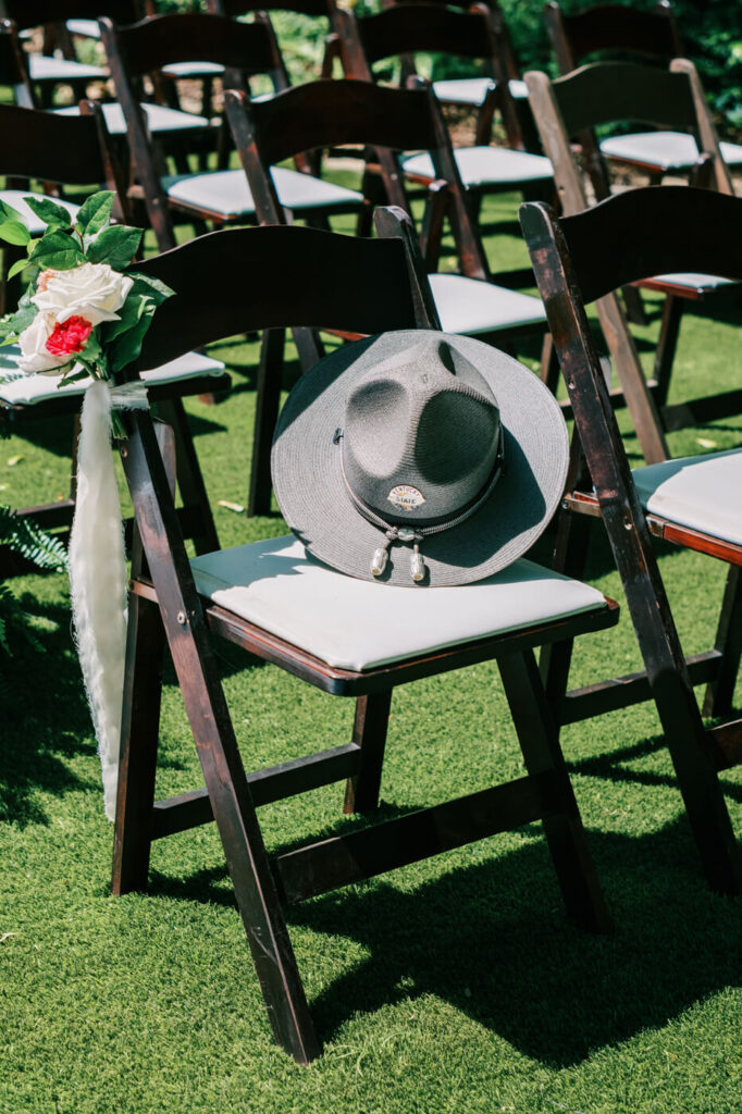 Close-up of a state trooper hat placed on a wedding chair for a sentimental tribute – A touching moment captured as brides fathers state trooper hat rests on a ceremony chair, symbolizing remembrance at this heartfelt wedding.