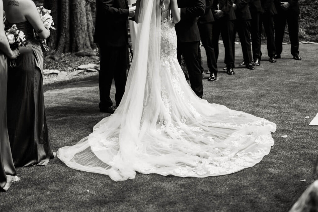 Bride's stunning lace wedding gown with cathedral veil at The Historic Robertson House – A detailed shot of the bride's flowing train and intricate lacework as she stands at the altar, framed by her bridesmaids.