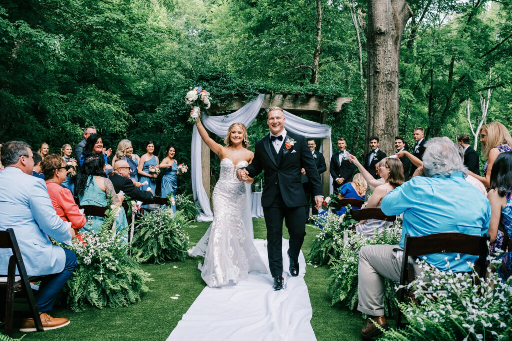 Newlywed couple joyfully walks down the aisle after their outdoor wedding at the Historic Robertson House, celebrating their love with friends and family.