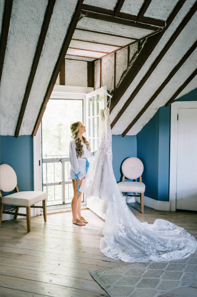 Bride admires her wedding dress in the bridal suite of Historic Robertson House, surrounded by elegant blue walls and natural light.