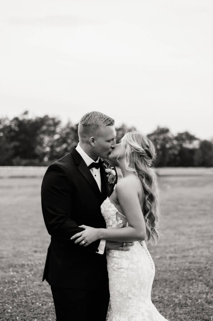 Black and white wedding kiss portrait – A timeless black and white image of the bride and groom sharing a romantic kiss in the countryside at The Historic Robertson House.