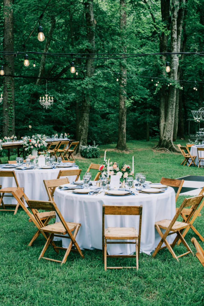 Elegant outdoor wedding reception at The Historic Robertson House – A beautifully styled reception setup with string lights, floral centerpieces, and candlelit tables under the canopy of towering trees.