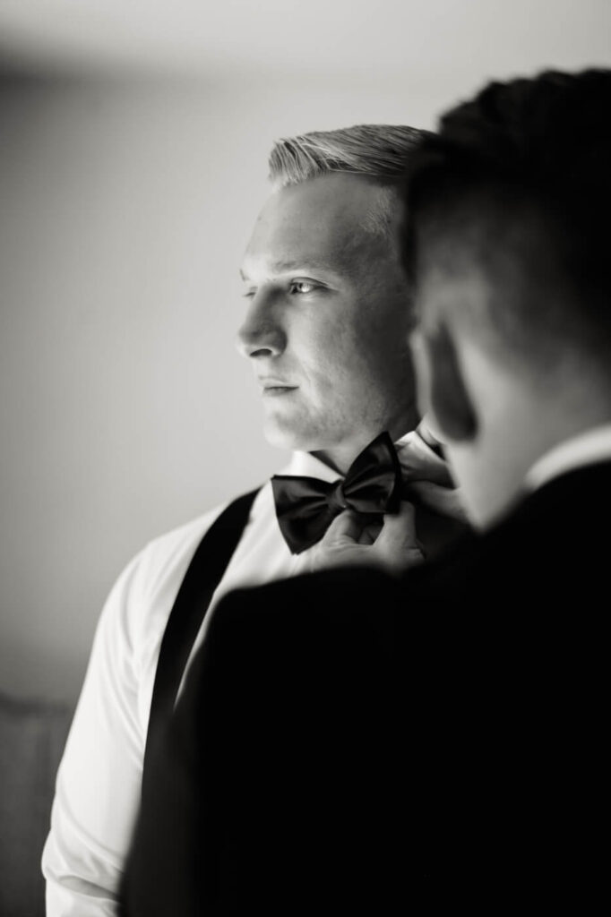 Groom adjusts his bow tie with the help of his best man before walking down the aisle at Historic Robertson House.